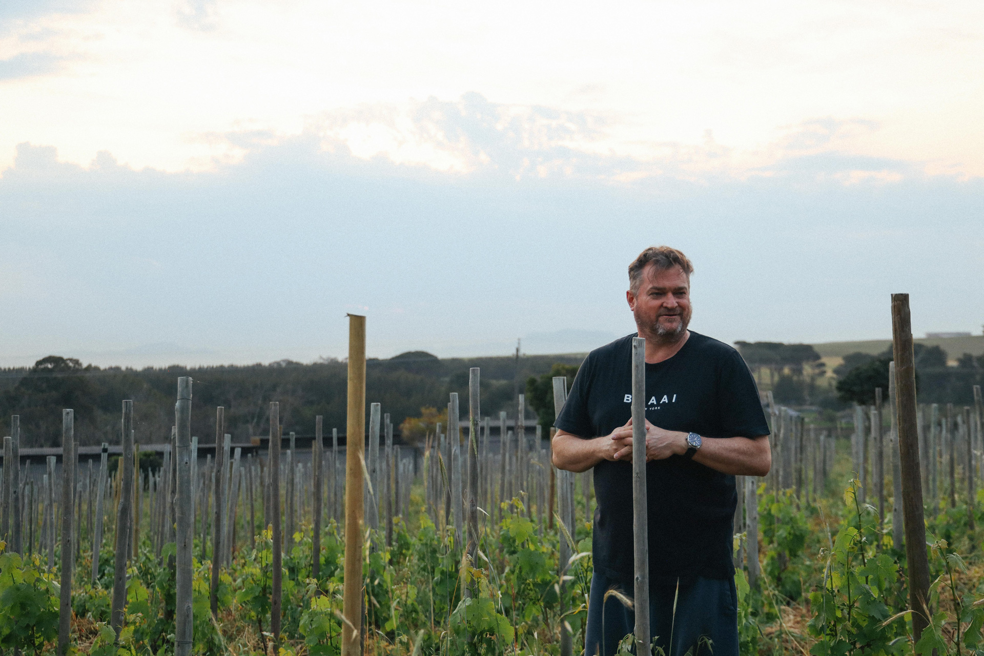 Photo of winemaker Bruwer Raats of Raats Family Wines in Stellenbosch, South Africa, standing in a vineyard.