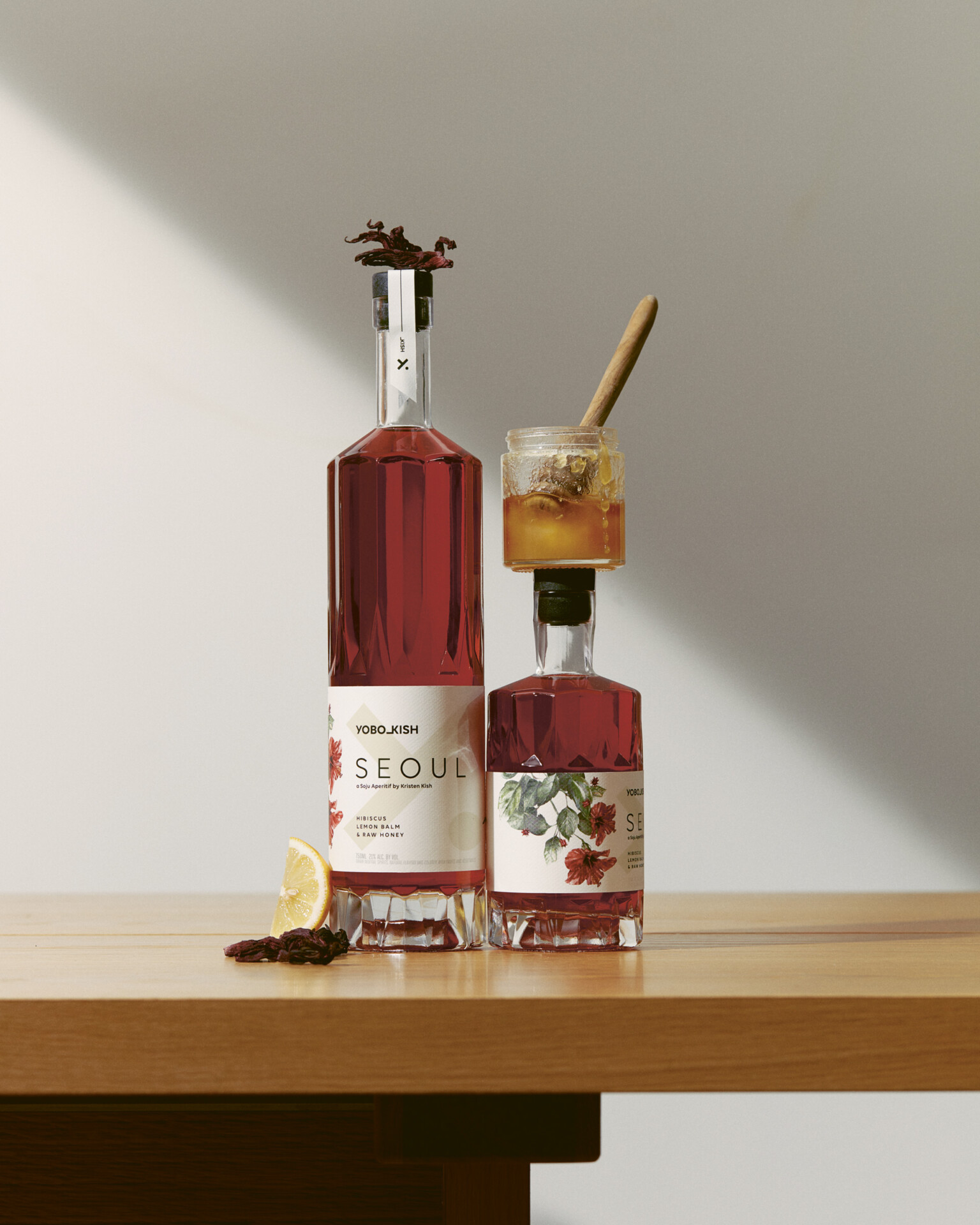 Two bottles of Yobo Kish Seoul Soju on a wood table, with tasting notes like honey, lemon and spice surrounding it.