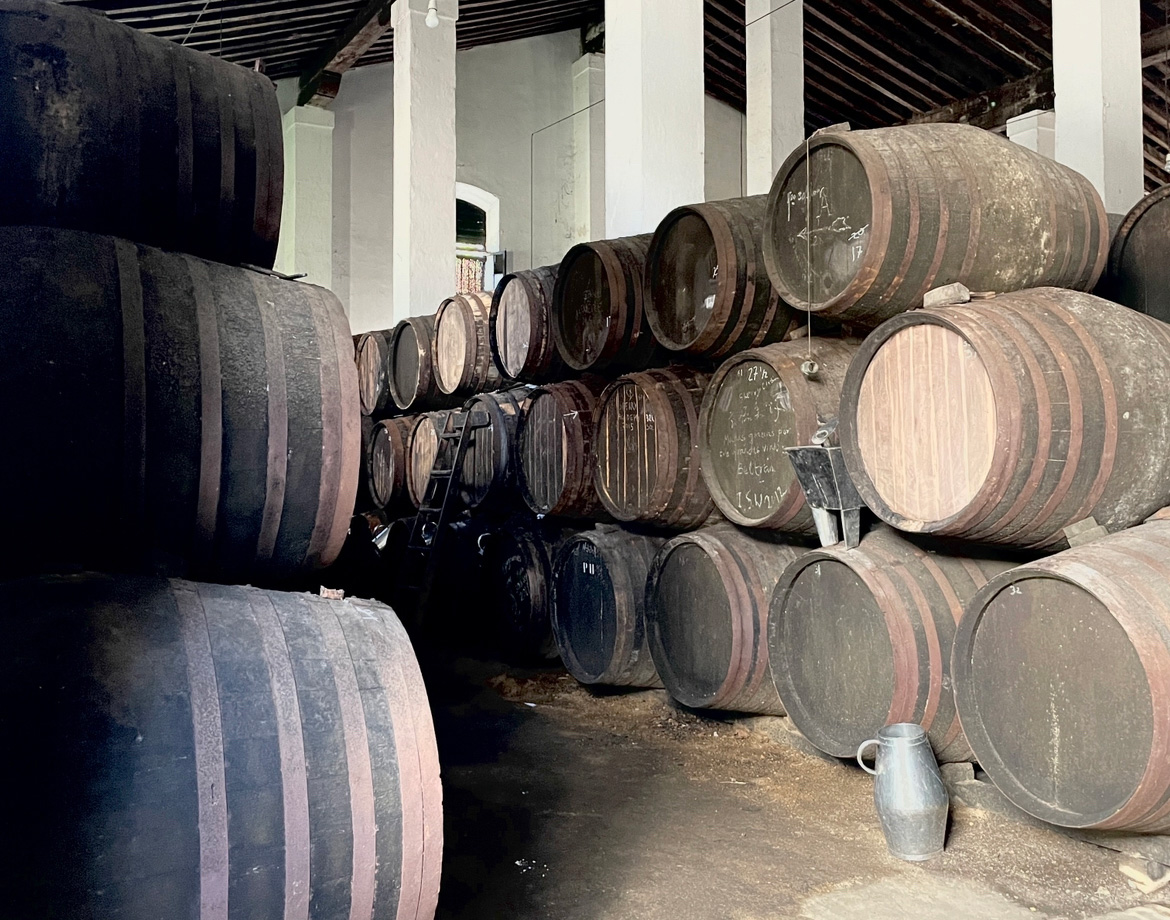 Pyramid-stacked wooden wine barrels (solera system) in a winery.