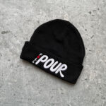 Full Pour black knit beanie hat with white logo embroidered on front rim