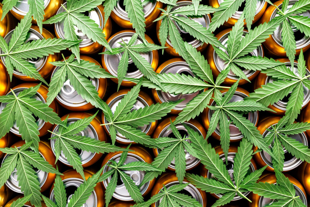 Photo of the tops of aluminum cans covered with cannabis leaves
