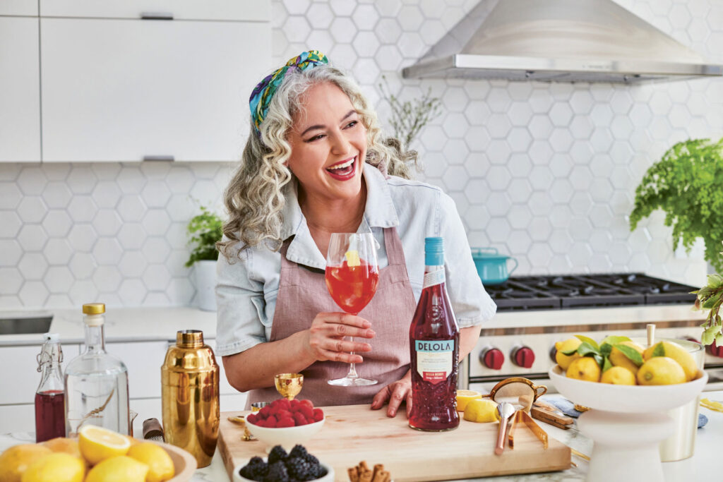 Lynnette Marrero raising a glass of Delola Spritz