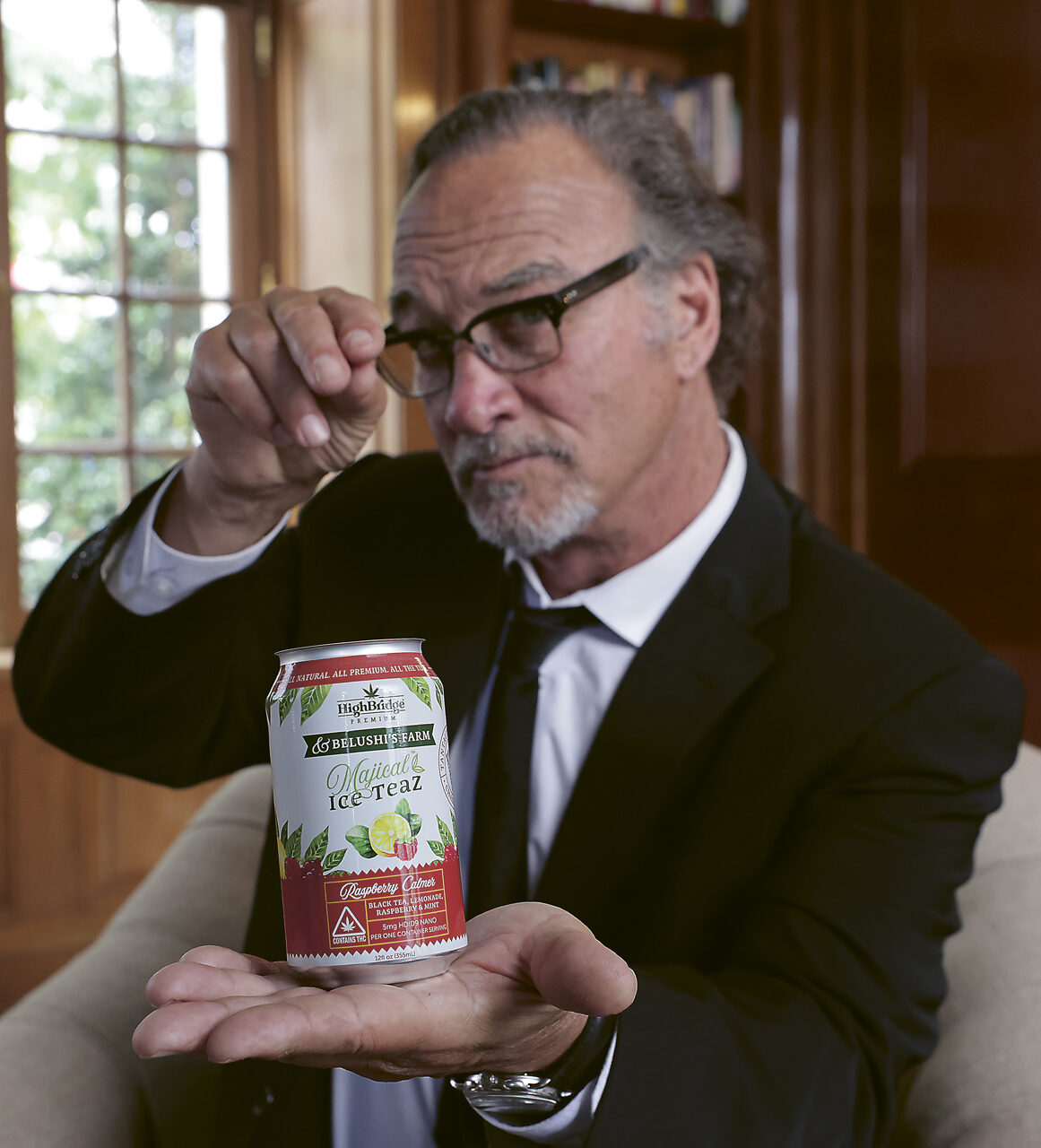 Photograph of Jim Belushi holding a can of Majical Ice Teaz, focused in the focused foreground