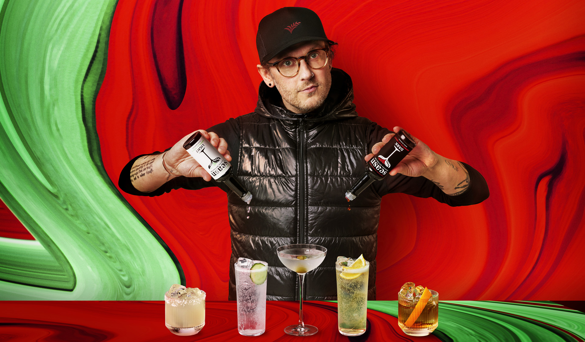 Ben Branson, founder of Seasn, standing with two bottles of Seasn in his hands, one light and one dark.