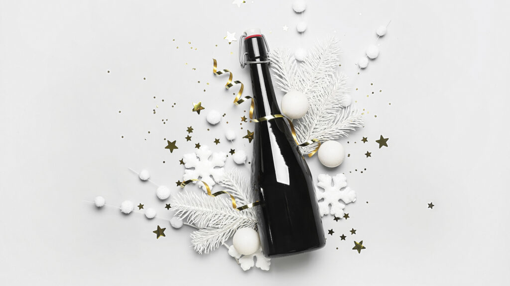 A picture of a Champagne bottle on a white background with holiday confetti surrounding it.