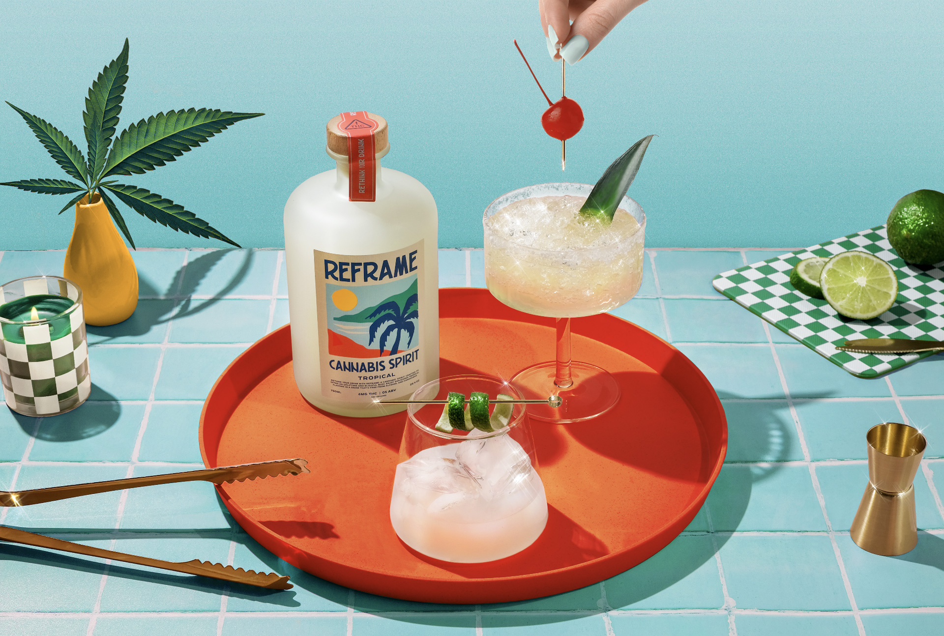 An orange tray set on a blue table and backdrop with a bottle of Reframe Cannabis Spirit and two cocktail glasses with drinks in them.