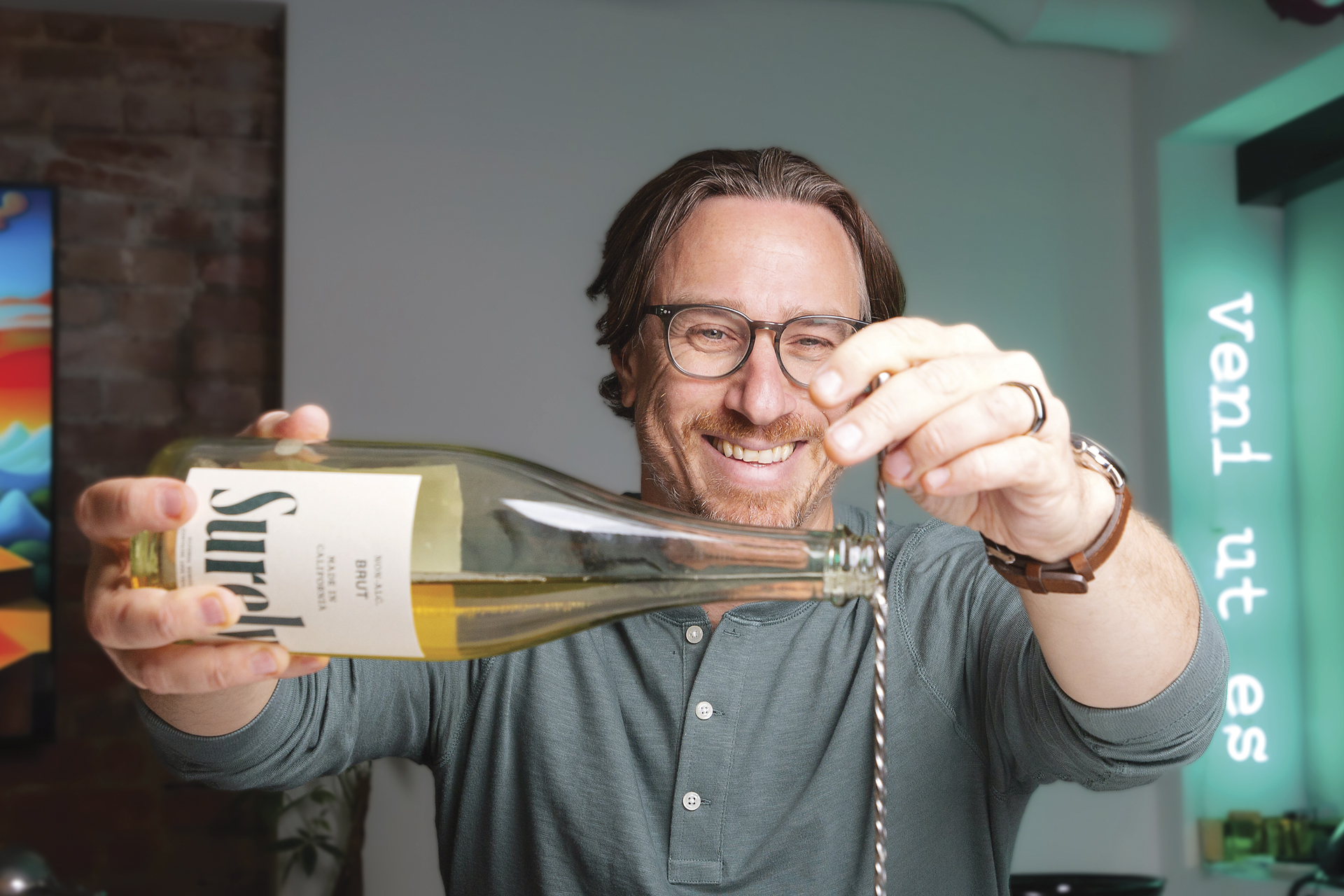 Mixologist Derek Brown seated and making a drink in front of him with Surely Nonalcoholic wine and a swizzle stirrer