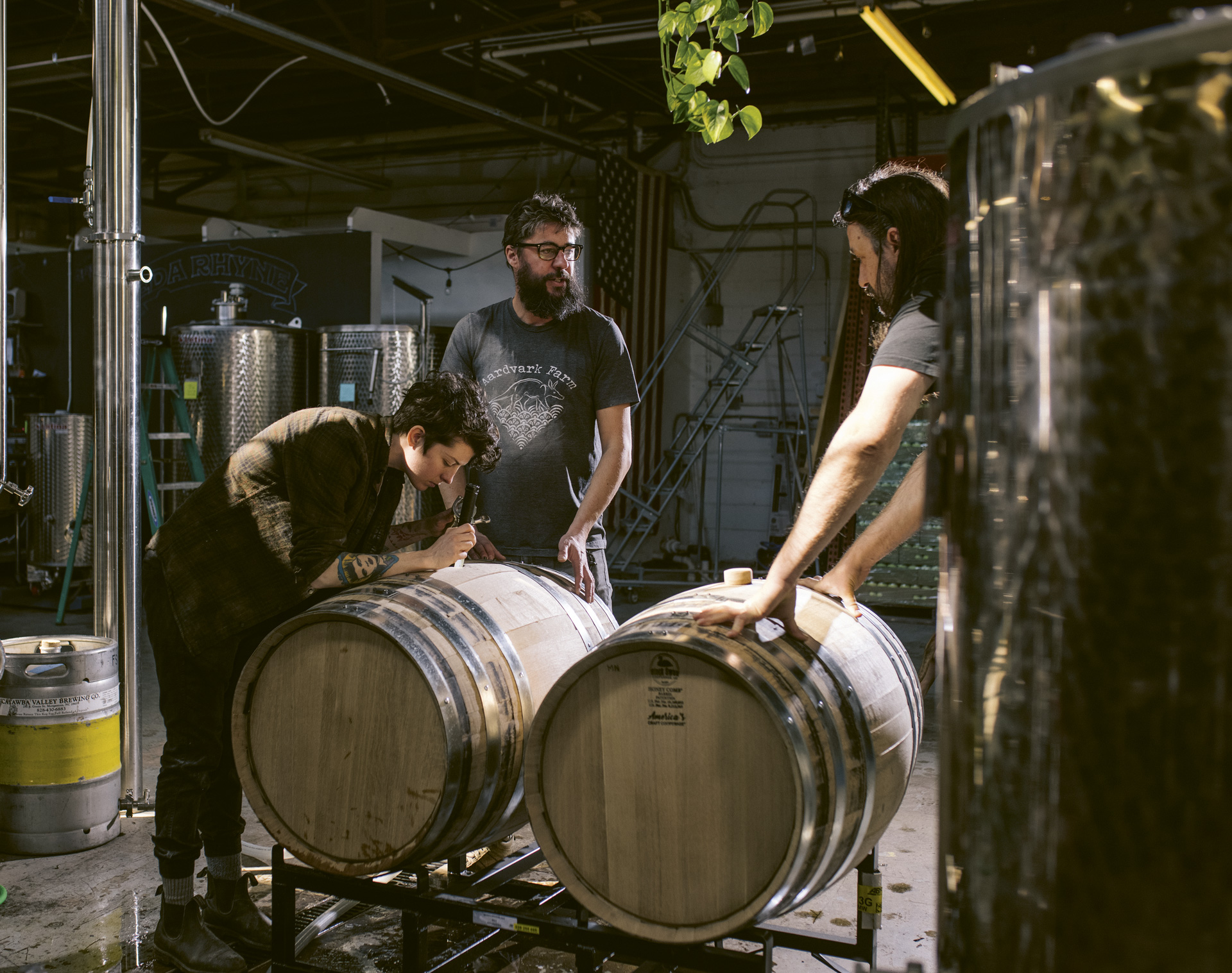 Eda Rhyne Lead Distiller Rider Burton, Rett Murphy and Chris Bower gathered over two oak barrels