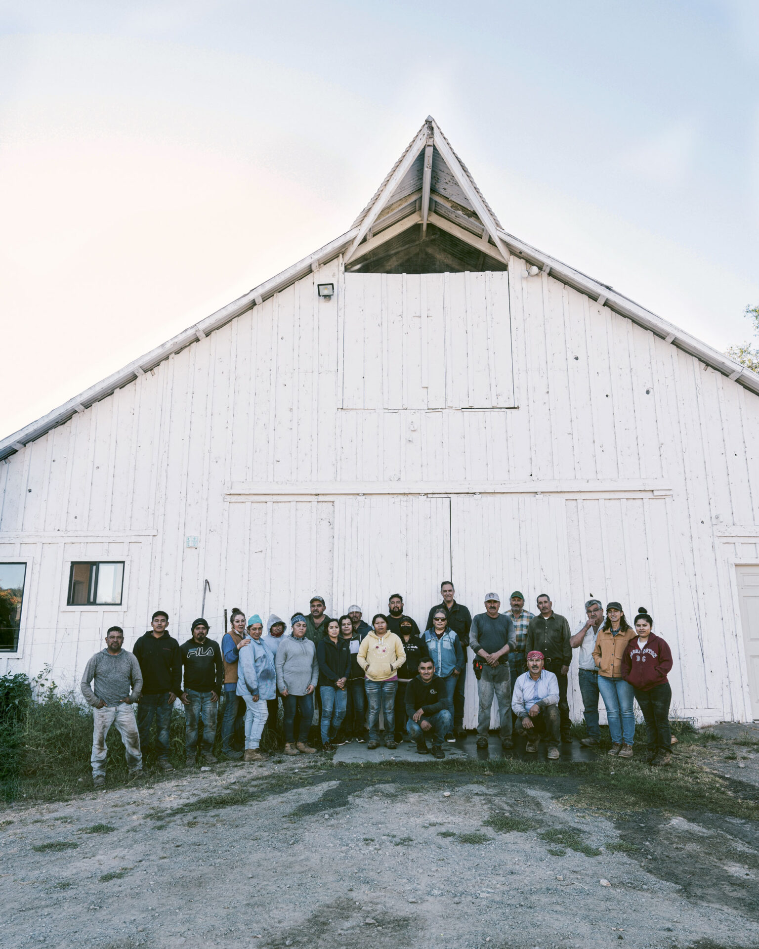 The Quintessa vineyard team on the first day of the 2023 red grape harvest, standing in front of a white winery building