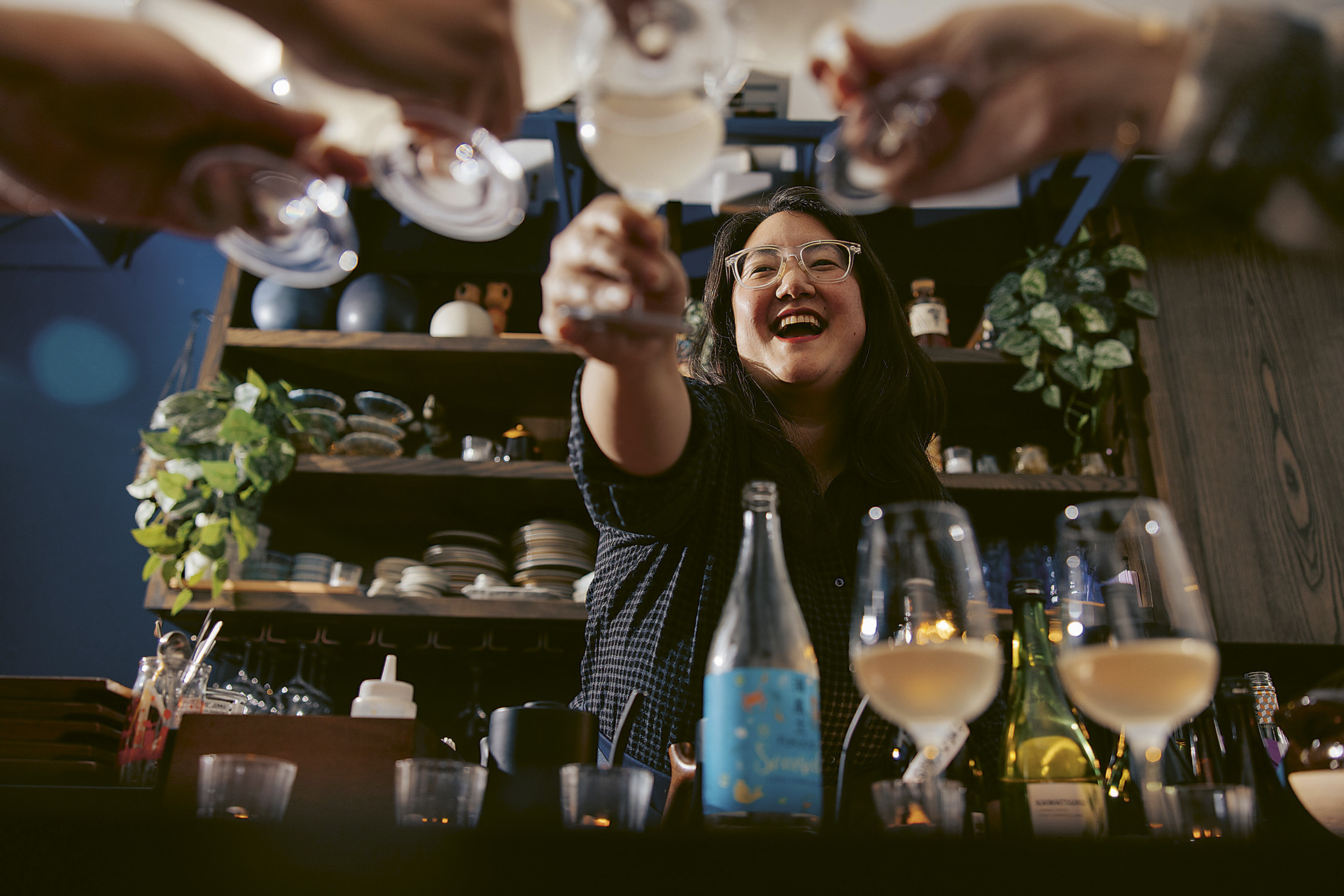 Alyssa DiPasquale cheersing with sake from across her bar at The Koji Club