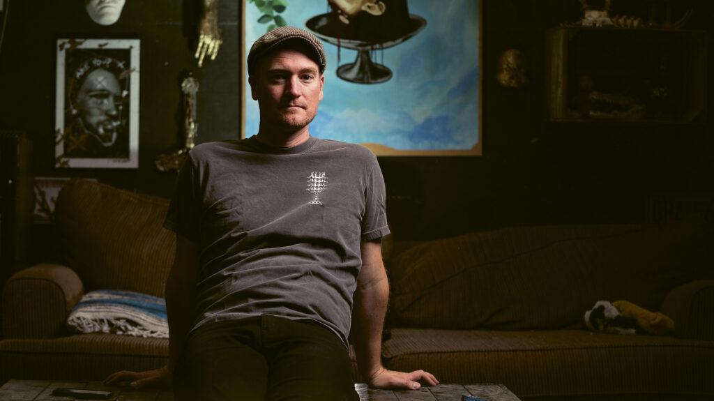 Photograph of Blood of Gods editor Stacy Buchanan, sitting atop a table in a dark setting
